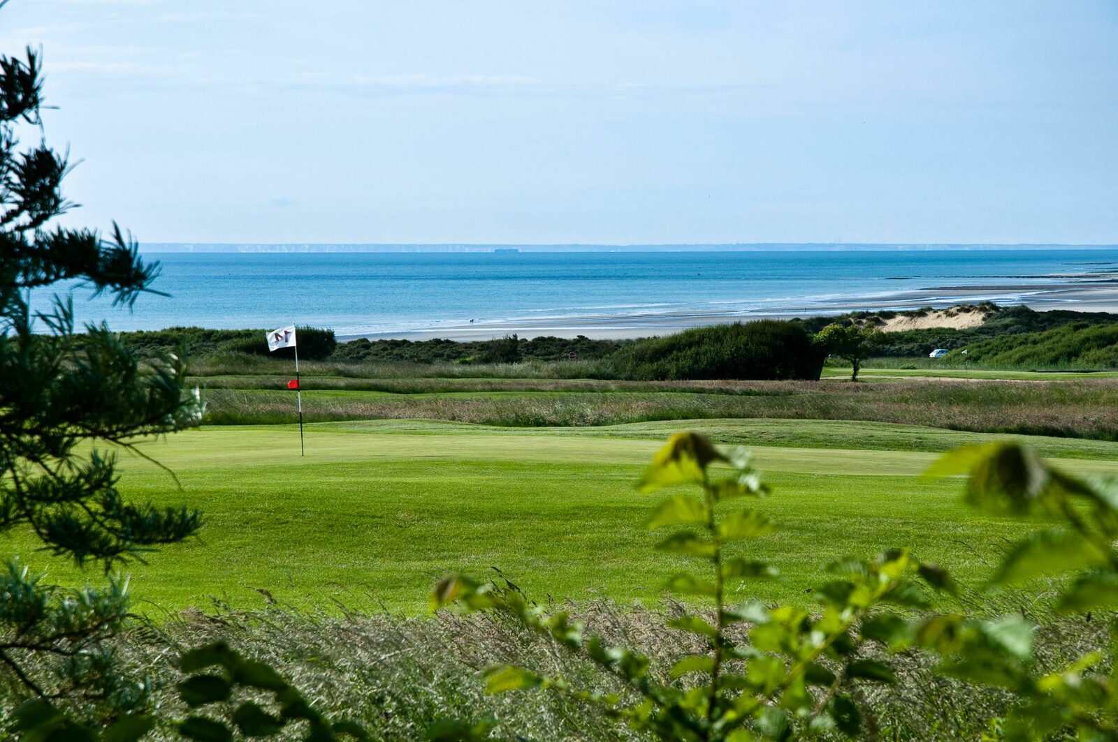 Terrain de golf de Wimereux par une journée ensoleillée avec la Côte d'Opale en arrière-plan.