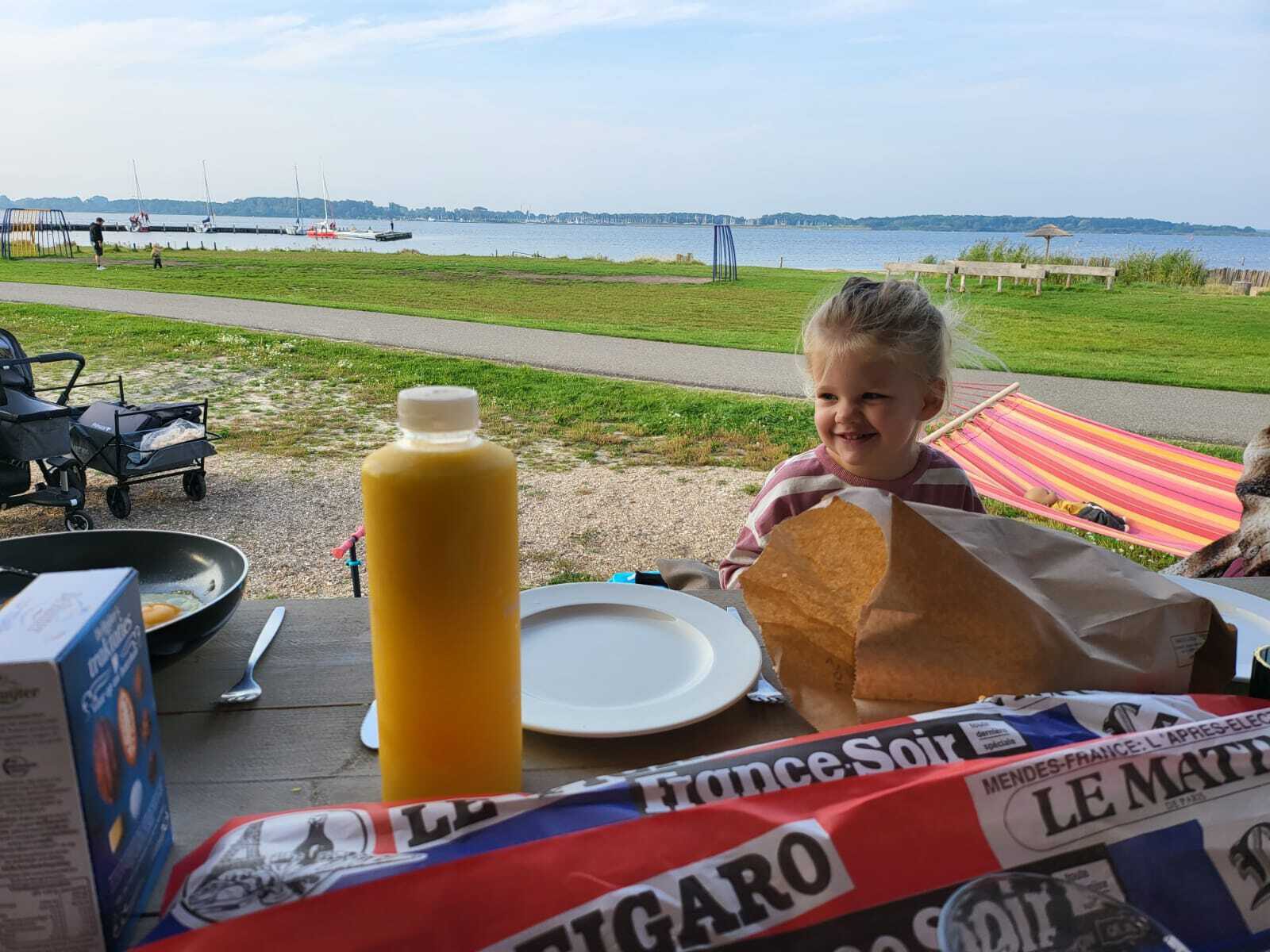 Ein Mädchen sitzt vor einem Safarizelt am Frühstückstisch