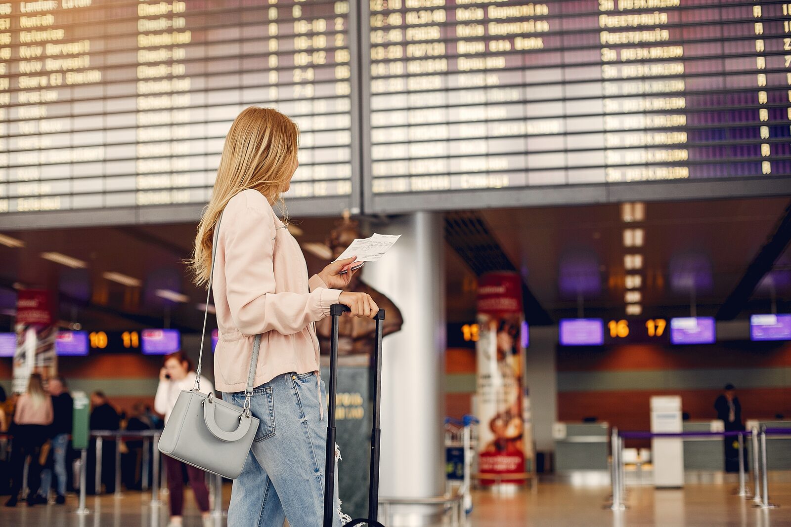 Jonge vrouw kijkt naar de informatieborden van de vluchten op de airport