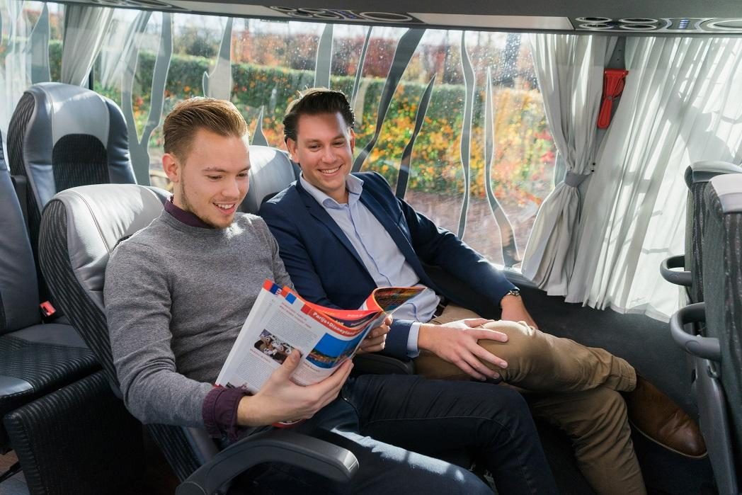 Twee mensen zittend in een bus met folder in de hand