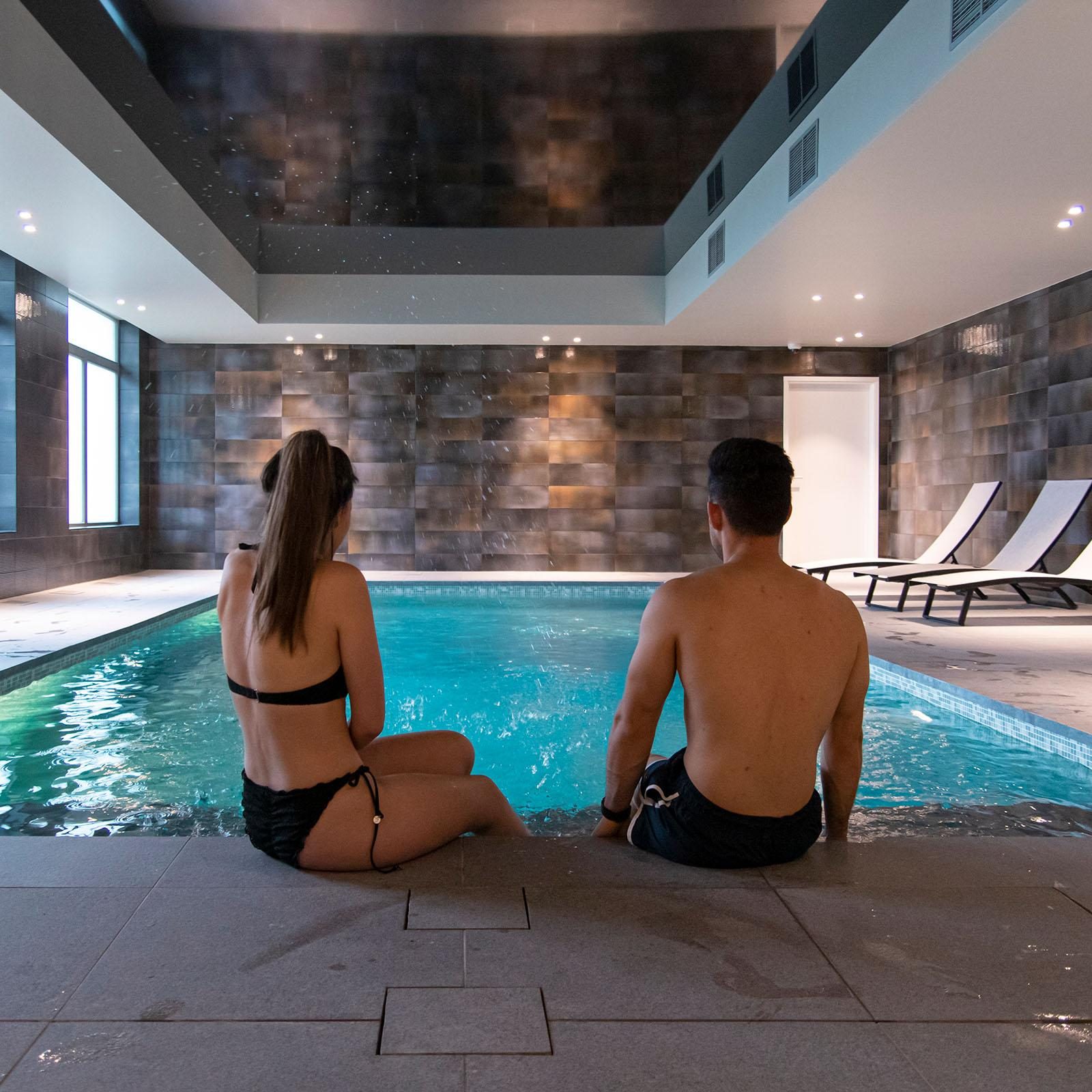Een man en een vrouw in het binnenzwembad bij Holiday Suites Zeebrugge