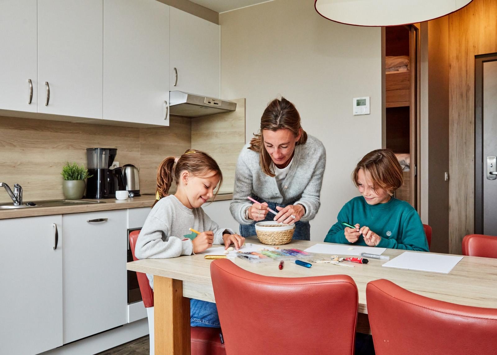 Een mama met haar twee kinderen aan het bakken in een vakantieappartement van Holiday Suites