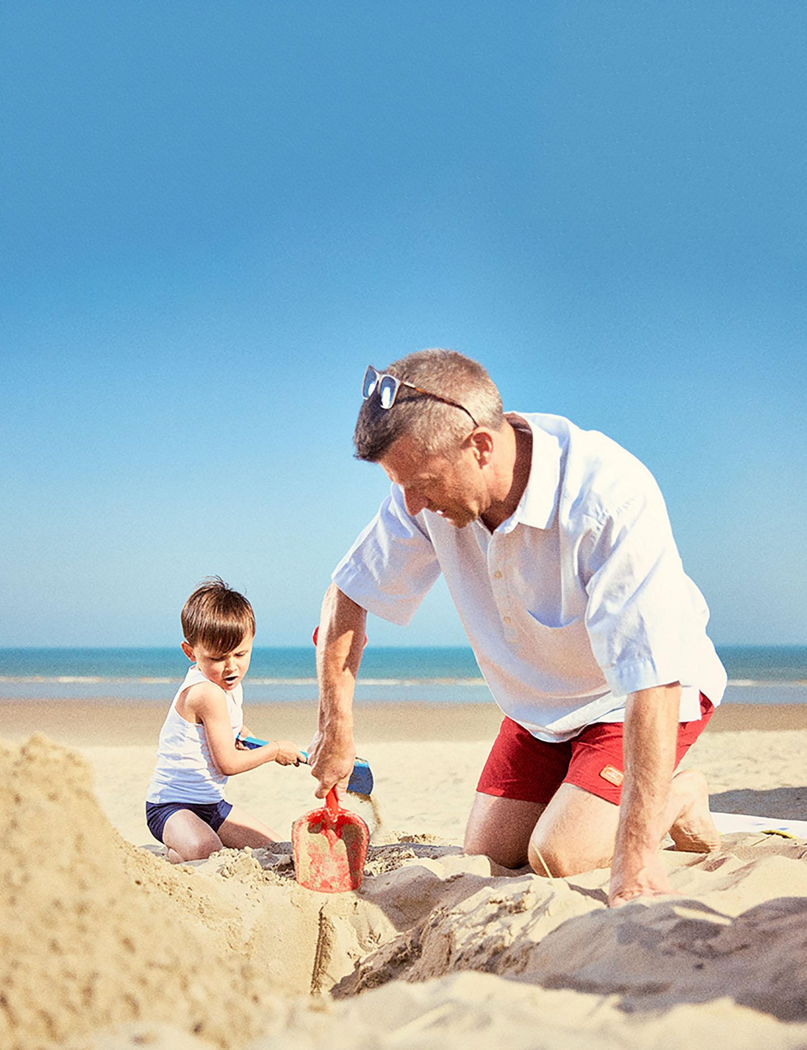 Een kindje en zijn opa spelen op het strand