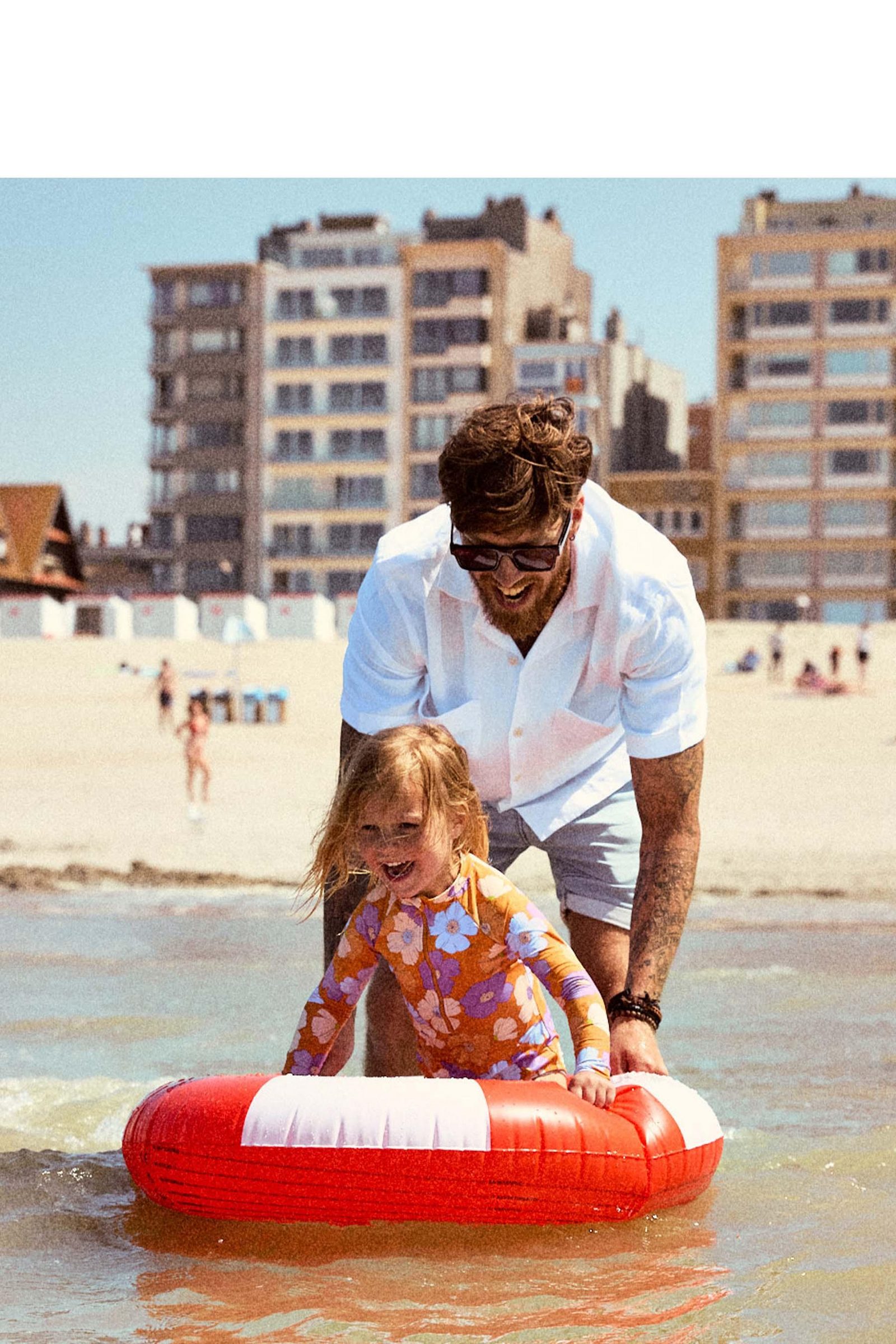 Een klein meisje speelt in de zee met haar papa