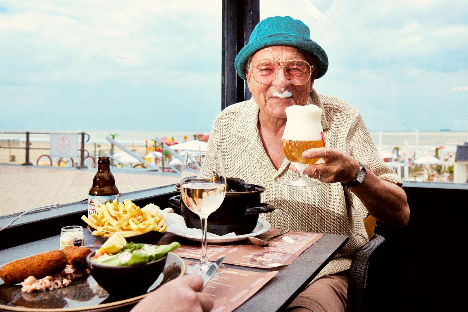 Een oudere man geniet van een restaurant op de dijk van Blankenberge